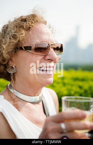 Close-up woman holding glass while standing against sky Banque D'Images