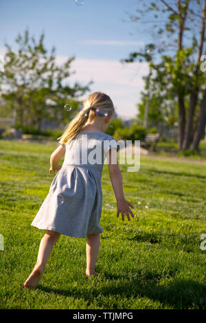 Vue arrière de fille qui marche sur terrain at park Banque D'Images