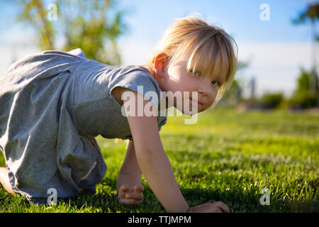 Portrait de jeune fille à genoux sur le champ à park Banque D'Images