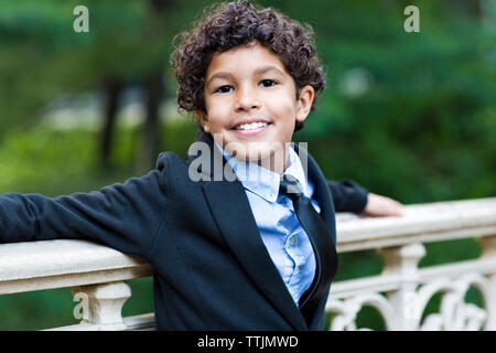 Portrait of boy standing by railing at park Banque D'Images