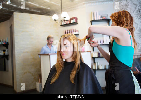 Vue latérale d'hairstylist cutting woman's hair salon Banque D'Images