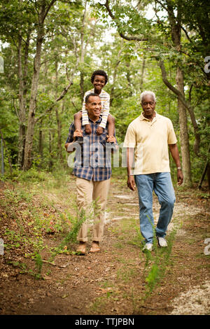 Man carrying son sur les épaules tout en marchant avec le père dans la forêt Banque D'Images