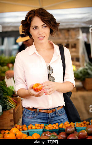 Thoughtful woman holding marché en faisant vos achats chez la tomate Banque D'Images