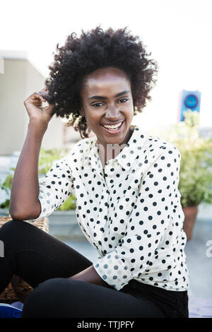 Portrait of happy woman sitting on terrasse de l'immeuble Banque D'Images