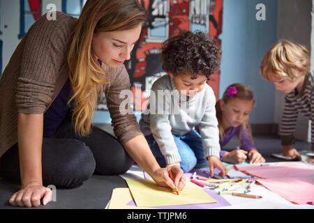 Dessin de l'enseignant sur les papiers avec les élèves à l'âge préscolaire Banque D'Images