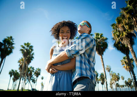 Low angle view of man embracing woman while standing against sky Banque D'Images