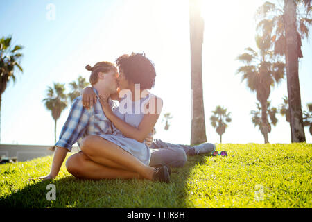 Affectueux couple assis sur terrain against sky Banque D'Images