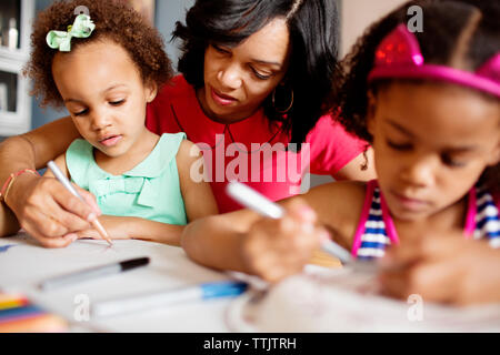 Mère d'aider leurs filles en dimensions à table Banque D'Images