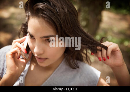 Thoughtful Woman talking on phone at park Banque D'Images