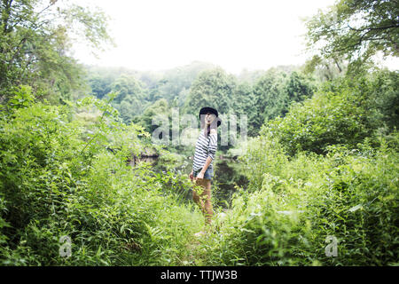 Woman looking away while standing in forest Banque D'Images