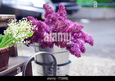 Peut-lily dans un panier sur la selle et lilas fleurs dans la benne Banque D'Images