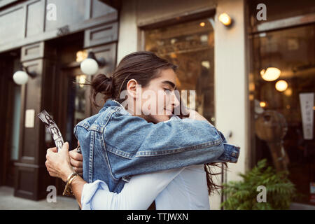 Fille Mère embrassant tandis que l'article de boutiques en ville Banque D'Images