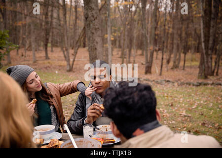 Couple having food avec des amis à table contre des arbres Banque D'Images