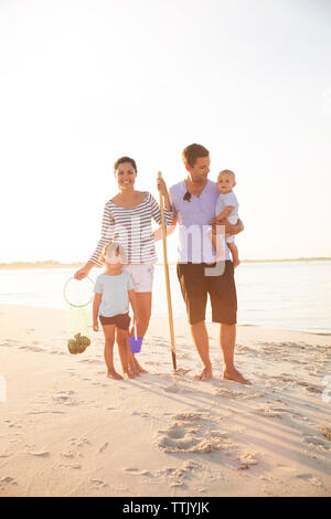 Toute la longueur de happy family standing on beach against clear sky Banque D'Images