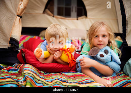 Portrait de famille avec des jouets en peluche couché dans la tente Banque D'Images