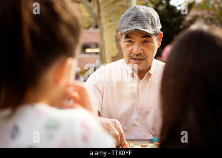 Grand-père jouer aux dames jeu alors que sitting at table in park Banque D'Images