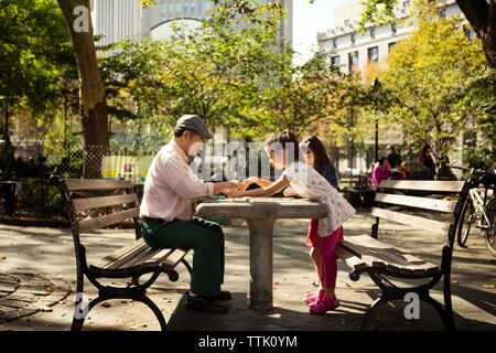 Vue de côté pour jouer aux dames jeu avec grand-père à table dans park Banque D'Images