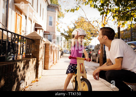 Père regardant girl pointing while sitting on bicycle Banque D'Images