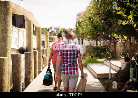 Vue arrière du gay men walking on boardwalk au cours de journée ensoleillée Banque D'Images