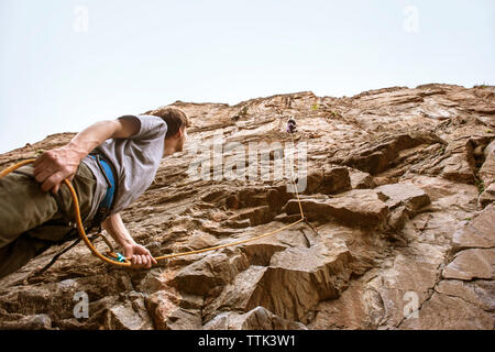 Low angle view of man looking at ami montagne escalade Banque D'Images