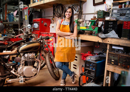 Portrait of happy female mechanic avec les bras croisés en se tenant debout dans l'atelier Banque D'Images