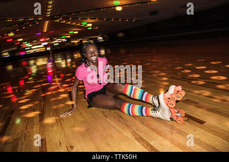 Happy woman wearing patins à assis à allumé roller rink Banque D'Images