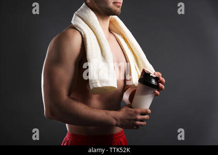 Jeune homme avec sports nutrition sur fond sombre Banque D'Images