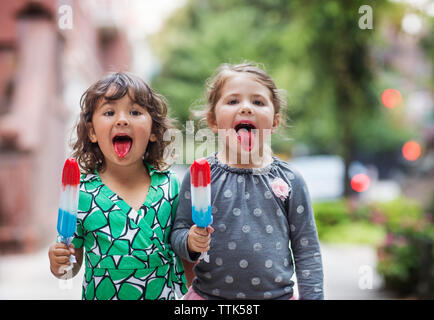 Portrait de filles sticking out tongue en maintenant sucettes glacées Banque D'Images