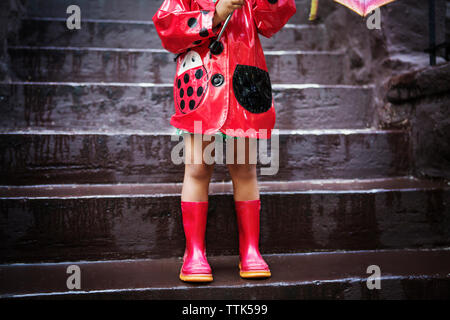 La section basse de girl wearing red imperméable et des bottes de l'article sur les mesures Banque D'Images