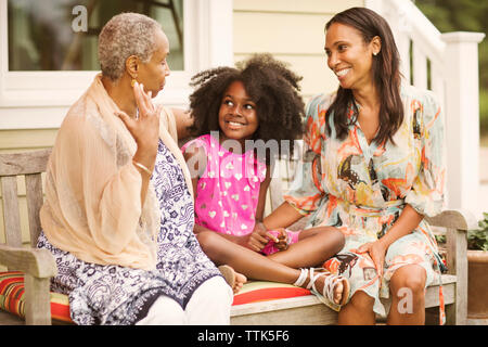 Fille assise avec mère et grand-mère sur le banc du patio Banque D'Images