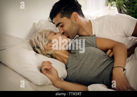 Jeune couple kissing on bed at home Banque D'Images