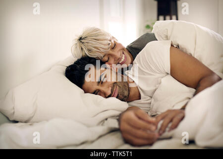 Happy young couple lying on bed at home Banque D'Images