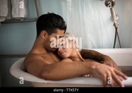 Young couple relaxing in bathtub at home Banque D'Images