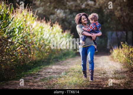 Mère exerçant son fils lors de la marche sur terrain Banque D'Images