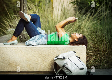 Woman using mobile phone while banc béton Banque D'Images