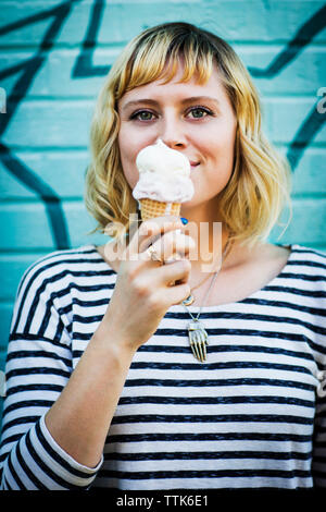 Close-up of woman holding ice cream debout contre le mur Banque D'Images