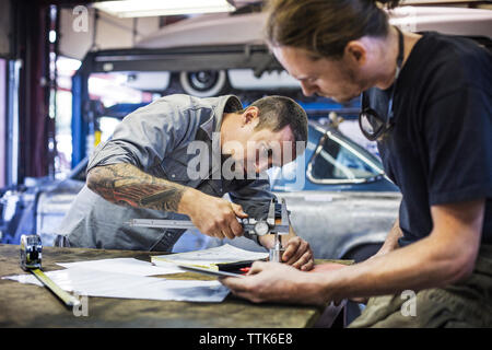 L'aide mécanicien pied à coulisse pour mesurer metal in auto repair shop Banque D'Images