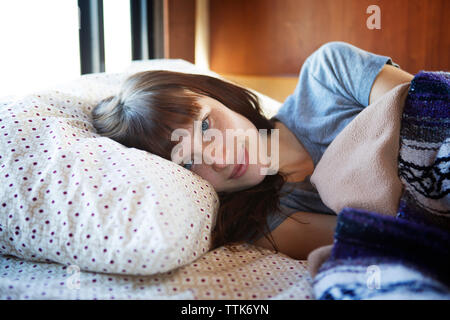 Portrait of woman lying on bed in camper van Banque D'Images