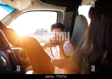 Man photographing femme à travers l'appareil photo instantané tout en restant assis dans le camping-car Banque D'Images