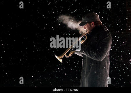 Vue latérale d'homme jouant de la trompette au cours de neige Banque D'Images