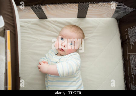 Portrait de frais généraux de mignon bébé garçon couché sur le matelas en pack n' play at home Banque D'Images