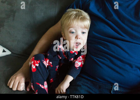 Bébé garçon regarde surpris assis à côté de père on couch Banque D'Images