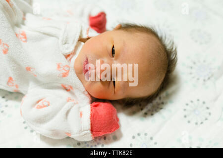 Newborn baby girl lying on blanket avec les yeux ouverts portant des gants Banque D'Images