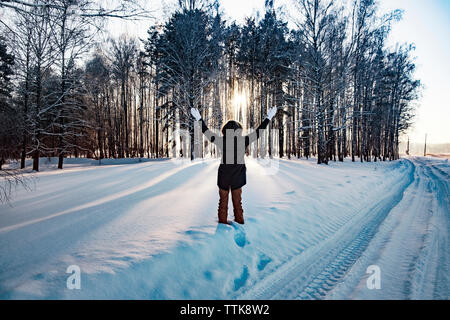 Vue arrière de femme debout avec les bras levés sur le terrain couvert de neige Banque D'Images