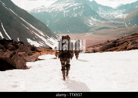 Vue arrière de la marche avec des sacs de randonnée en montagne en hiver Banque D'Images