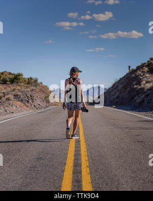 Jeune Femme photographe marcher au milieu de la route Banque D'Images