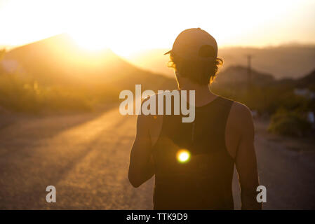 Jeune homme qui marche sur la route le matin du lever ou coucher du soleil Banque D'Images