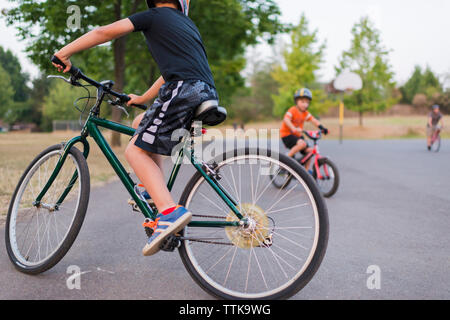 Frères la bicyclette sur route contre des arbres en parc Banque D'Images
