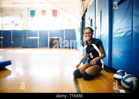 Portrait of smiling teenage girl sitting on floor in volley Banque D'Images