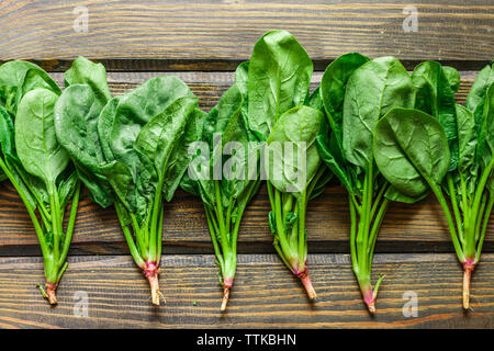 Épinards frais biologiques récoltés sur une table en bois sombre. Les légumes verts avec des gouttes d'eau. Selective focus, copy space Banque D'Images